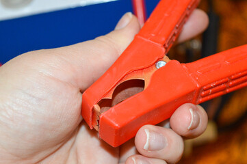 hand holding red jumper cable clamp battery system connected wiring setting technical electrical environment energy storage automotive repair off-grid power solutions charging upkeep renewable energy 