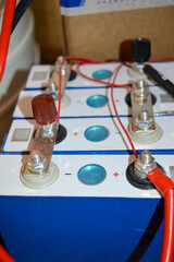 DIY custom battery pack setup lithium-based LiFePO₄ cells red and black wires indicate power connections blue wires monitoring balancing plug charging energy storage system off-grid power solutions 