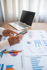 A young Asian businessman is examining financial documents to determine investment returns and...