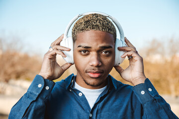 Young Guy Looks At Camera With Headphones In A Park
