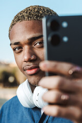 Portrait of a young afro guy looking at the camera with confident expression with his mobile in his hand