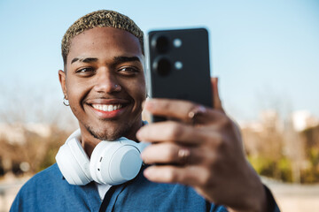 Young boy smiling looking at his mobile in a park