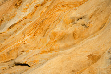 Natural texture background of sandstone rocks with lines, curves, prints in the As Amoeiras and Formosa beach cliffs in Santa Cruz, Portugal.