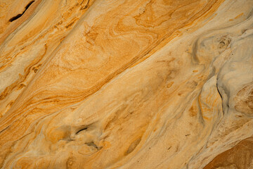 Natural texture background of sandstone rocks with lines, curves, prints in the As Amoeiras and Formosa beach cliffs in Santa Cruz, Portugal.