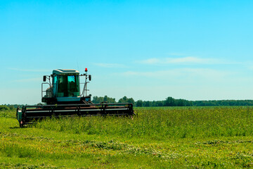Fototapeta premium A tractor is driving through a field of grass