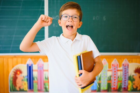 Cute schoolboy near blackboard in classroom