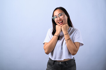 A cheerful young Asian woman with glasses and long dark hair, wearing a white crop top, posing with...