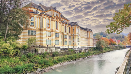 Historic yellow building by the river in Feldkirch Austria surrounded by autumn foliage under a...