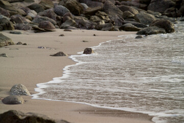sand beach rocks and sea Waves of the undertow in Porticciolo. Alghero. Sardinia. Italy