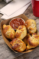 Italian garlic bread knots with marinara dipping sauce in food basket on rustic wood surface