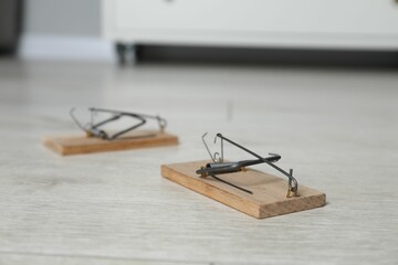 Spring-loaded bar mousetraps on floor indoors, selective focus