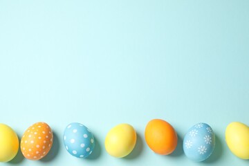 Beautiful decorated Easter eggs on light blue background, flat lay. Space for text