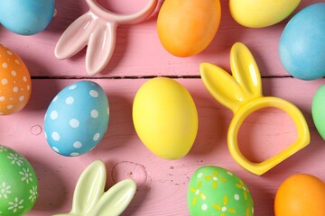 Beautiful decorated Easter eggs and bunny figures on pink wooden table, flat lay