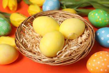 Easter eggs and beautiful tulips on orange background, closeup