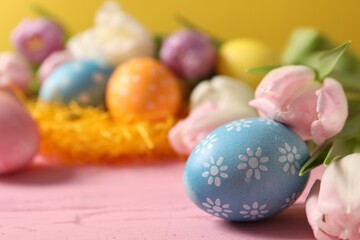 Easter eggs and beautiful tulips on pink wooden table, closeup. Space for text