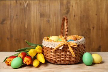 Easter eggs in wicker basket and beautiful tulips on wooden table