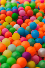 Background of many mixed plastic colored and multicolored round balls in children's playroom for kids to play. Close-up photo, childhood concept, abstract.