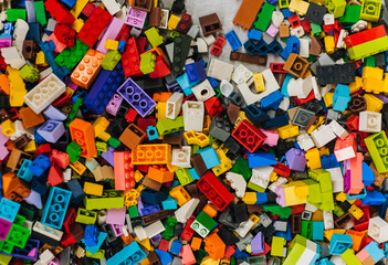Background, texture, close-up photograph of a top view of multi-colored parts, accessories of a plastic children's construction set.