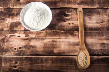  Flour in a bowl with ears and grains on wooden background