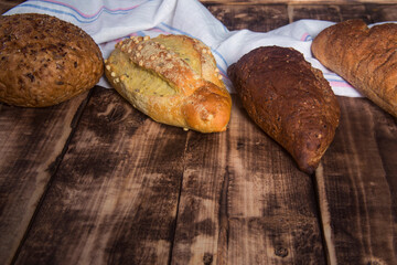 Assortment of baked bread on wooden table background