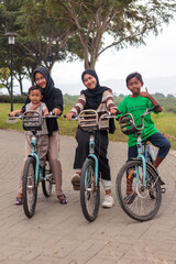 Fototapeta premium Happy Muslim Family Riding Bicycles in the Park Outdoors