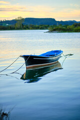Fototapeta premium Serene boat floating on tranquil lake at sunset