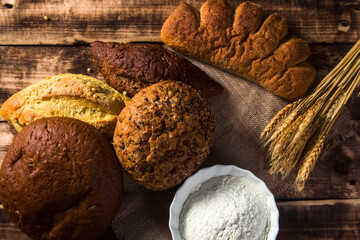 Assortment of baked bread on wooden table background