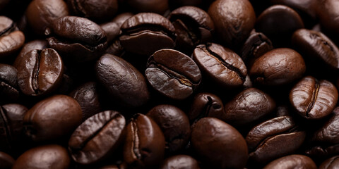 Naklejka premium Nahaufnahme gerösteter Kaffeebohnen mit glänzender, aromatischer Oberfläche auf hellem Hintergrund