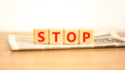 Stop symbol. Concept word Stop on beautiful wooden blocks on newspaper. Beautiful wooden table...
