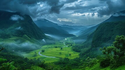 Obraz premium A vast verdant valley framed by towering misty mountains, where nature thrives under a dramatic sky.