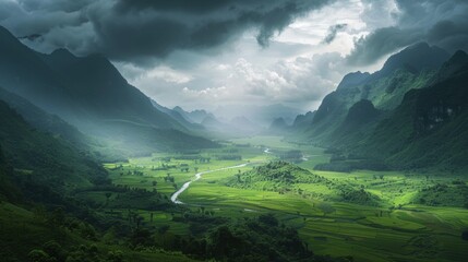 Obraz premium A vast verdant valley framed by towering misty mountains, where nature thrives under a dramatic sky.