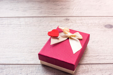 red gift box place near heart shape on the wooden floor in concept of Valentine day.