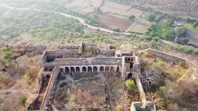 Aerial top view of ruined Pathrigarh Fort in India situated ay hilltop and mountains all around it 