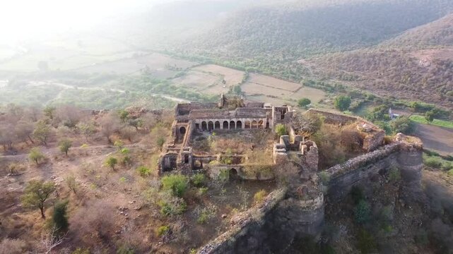 Drone view of ruined Pathrigarh Fort in India situated ay hilltop and mountains all around it 