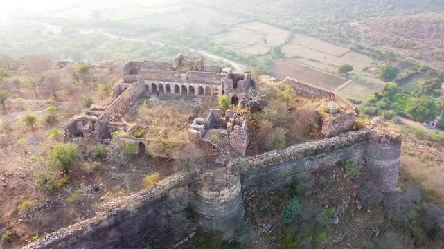 Aerial view of ruined Pathrigarh Fort in India situated ay hilltop and mountains all around it 
