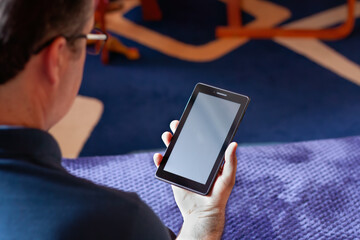 Man using a tablet with a blank screen indoors
