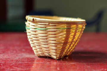 Fototapeta premium Handwoven Bamboo Basket on a Rustic Red Table