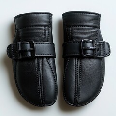 A pair of stylish black leather mittens featuring adjustable buckle straps on a white background. Protecting hands from the cold with a chic and sophisticated touch.