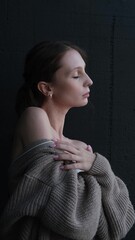 Portrait of a beautiful young girl with bare shoulders on a dark studio background. Beautiful...