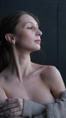 Portrait of a beautiful young girl with bare shoulders on a dark studio background. Beautiful...