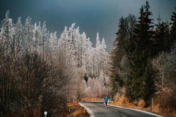 Winter endurance training in the wilderness, a lone runner on frosty road.