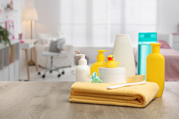Baby cosmetic products and bath accessories on table in room. Space for text