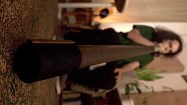 Close-up young man plays the didgeridoo in his home studio 4K