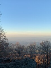 A stunning mountain landscape with bare trees and a soft sunset glow, offering a peaceful and serene atmosphere.