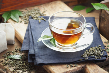 Green chinese tea with fresh leaves, hot drink on black background, closeup, natural medicine and...