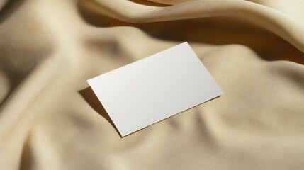 Blank Business Card Mockup - A clean, white business card rests on a beige fabric backdrop, creating a minimalist and elegant design