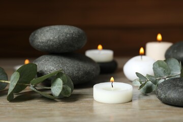Beautiful composition with burning wax candles, stones and eucalyptus on the tablе