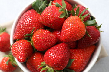 Delicious fresh red strawberries in a bowl on a wooden background