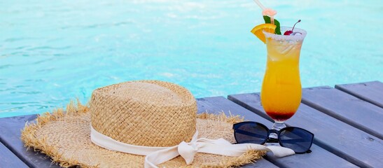 A nice cocktail, hat and sunglasses by the pool