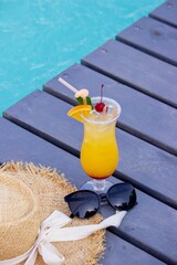 A nice cocktail, hat and sunglasses by the pool